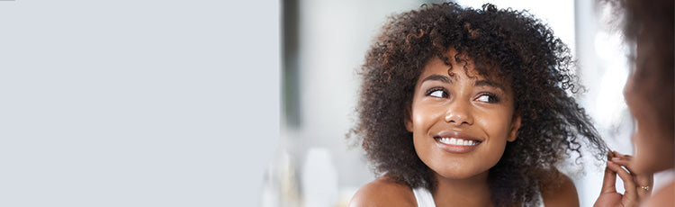 Smiling woman with curly hair looking in the mirror