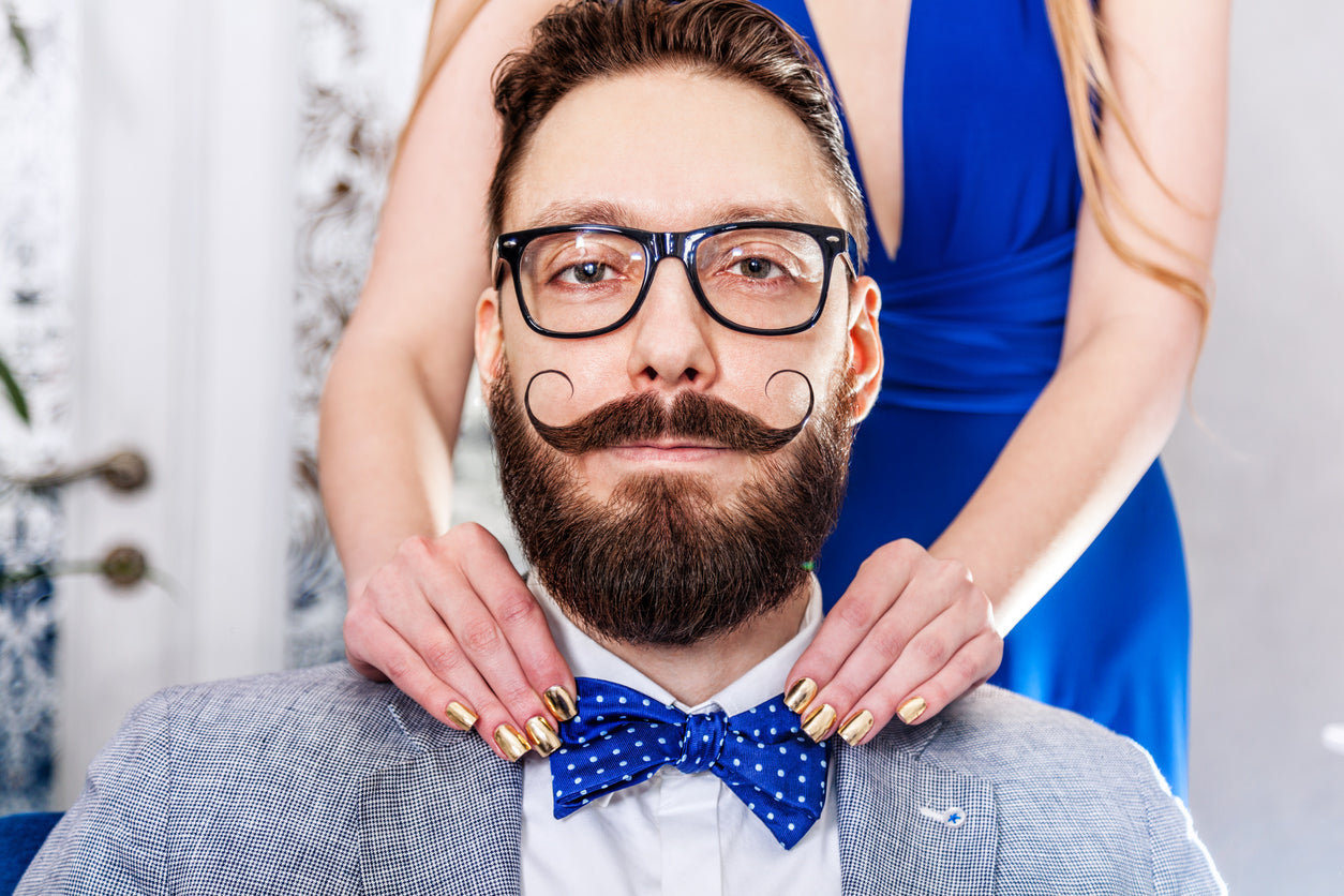 Man in a suit with glasses with a groomed beard and mustache