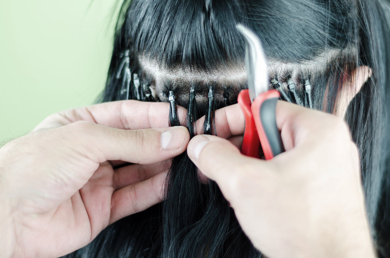 Woman getting fusion or bonded hair extensions applied.