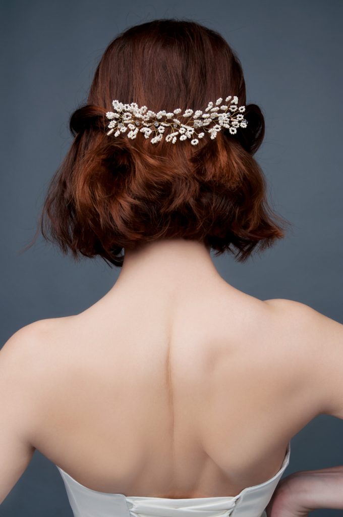 Back view of a bride with a short wedding hairstyle, half pulled back in a beaded clip.