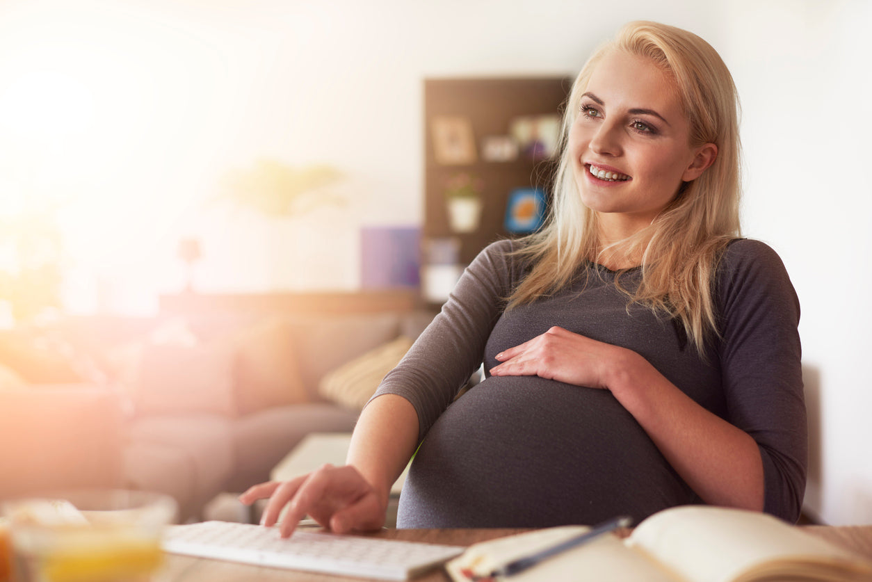 Pregnant woman sitting down with her hand on her belly