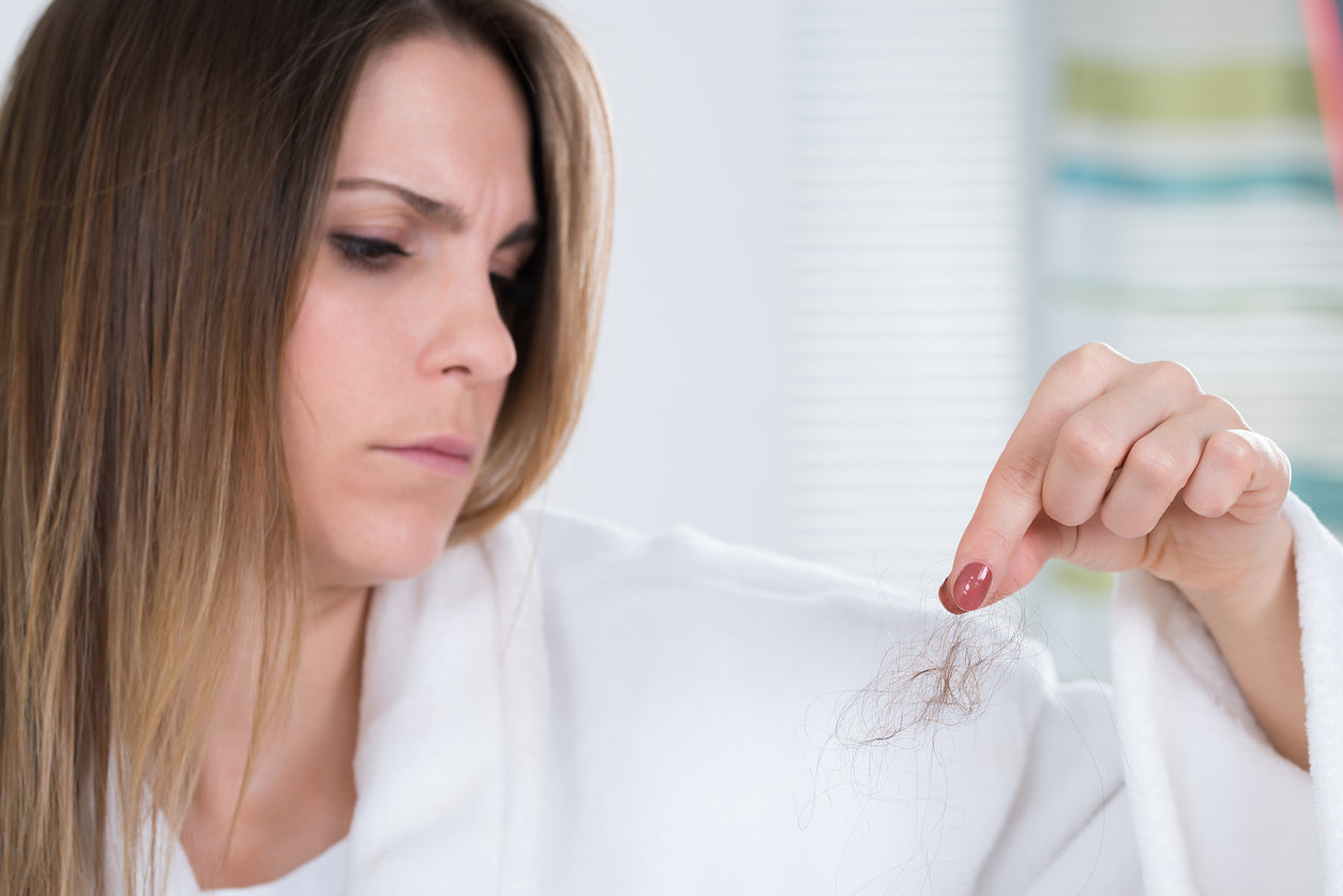 woman holding a piece of her shedding hair
