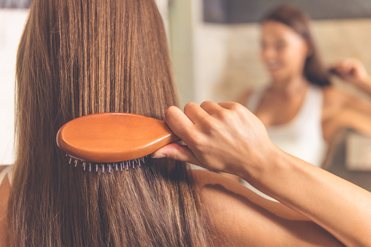 woman brushing her hair in front of a mirror