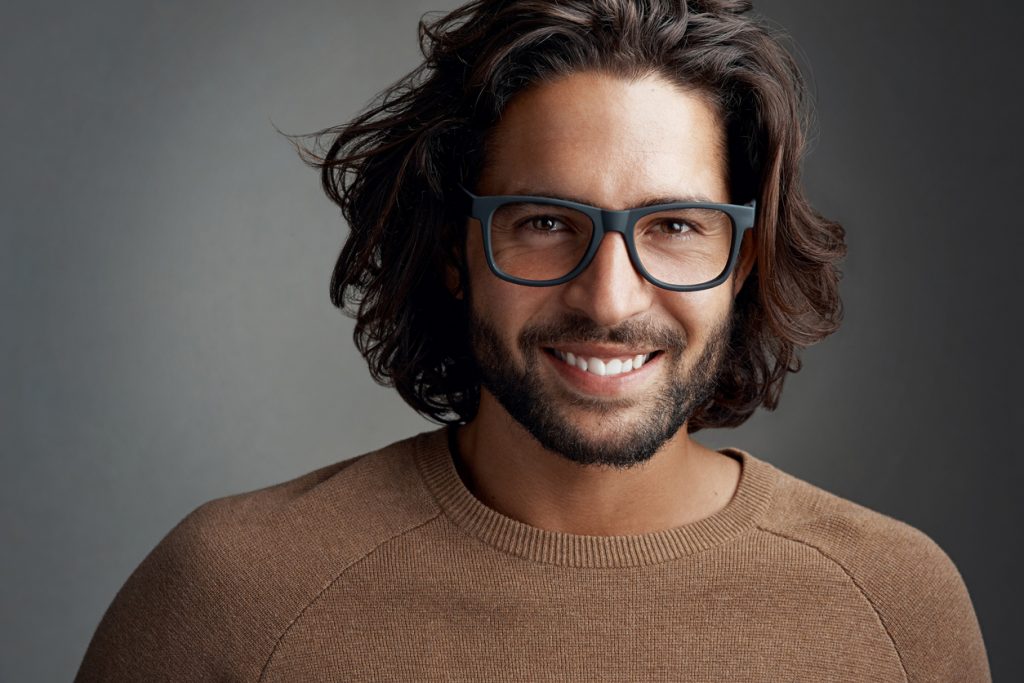 closeup man long shag haircut brown hair black frame glasses tan sweater dark gray background shag haircuts for men and women toppik hair blog