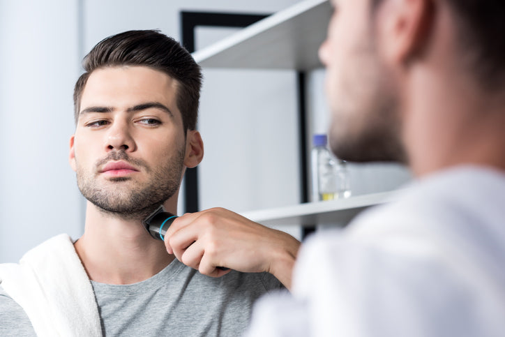 man looking at the mirror trimming his beard