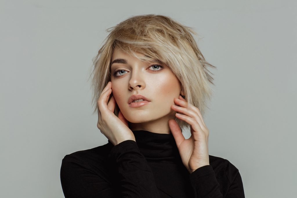 woman blonde short shag hair with bangs black turtleneck gray background shag haircuts for men and women toppik hair blog