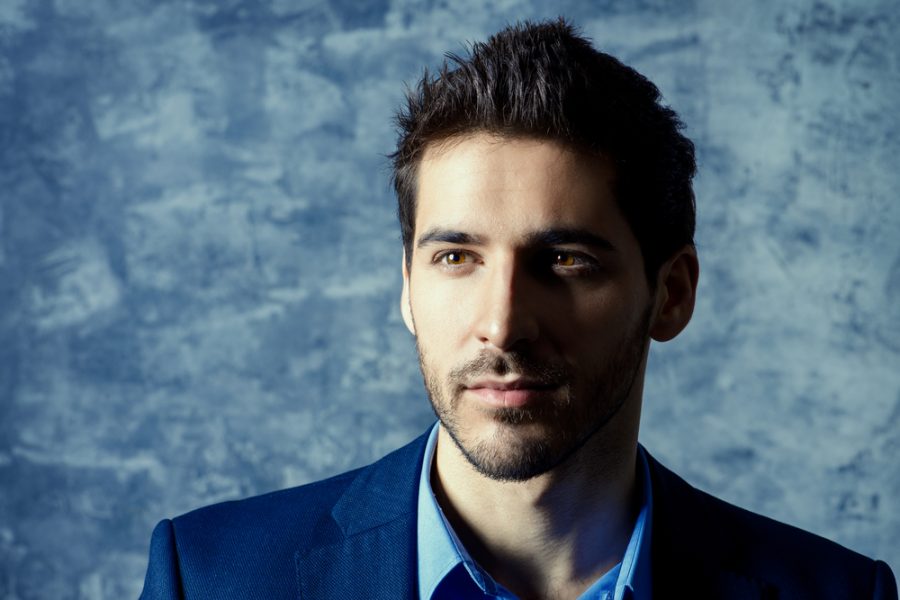 closeup handsome man dark shadows face spiky brown hair boy band hairstyle blue textured background 2020 hair trends for men and past styles toppik hair blog