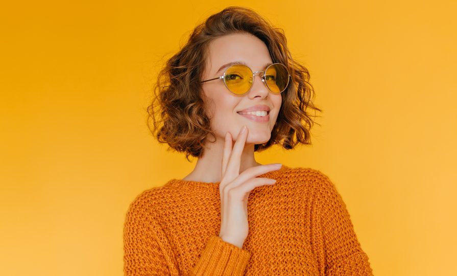 orange background woman smiling curly hair short chin length wavy bob our favorite wavy hairstyles toppik hair blog