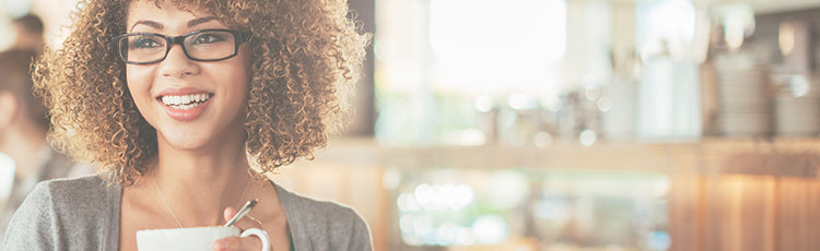 smiling woman curly hair glasses coffee cup cafe caffeine hair growth toppik hair blog