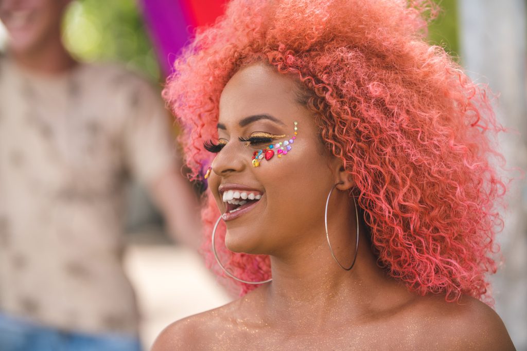 smiling woman pink coral hair african american jewel face makeup fall hair  colors trends toppik hair blog