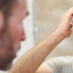 A man styles his hair in the mirror. How to add volume to thin hair.