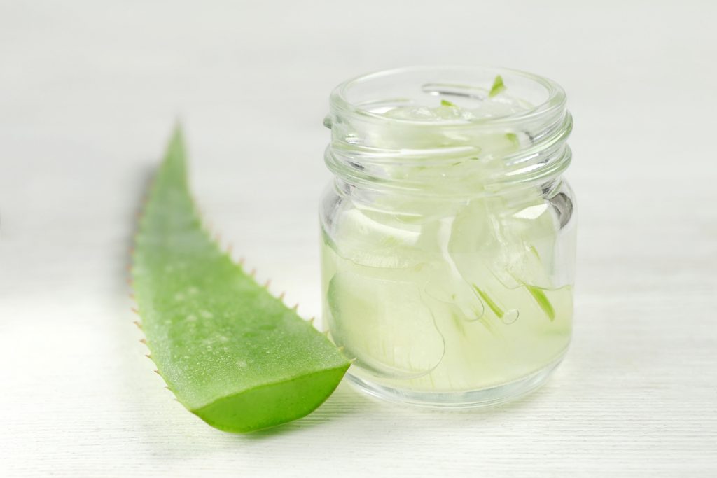 Aloe vera slice on table and aloe gel in clear glass jar best shampoo for hair growth and thickening toppik hair blog