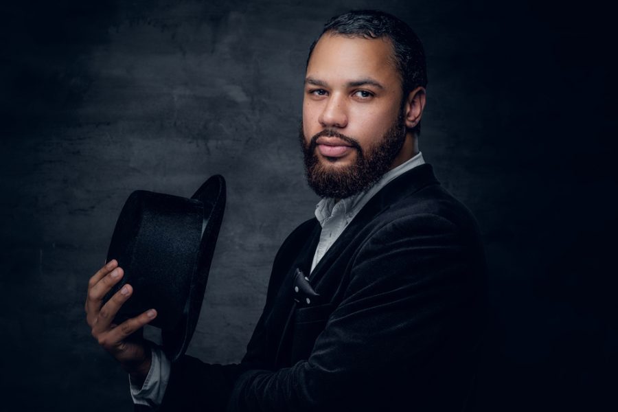 handsome african american man holding hat beard dark background velvet jacket prepare for 2020 with 1920s hairstyles toppik hair blog