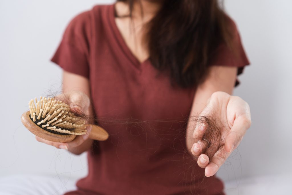 woman hair loss shedding hand brush maroon shirt cropped can stress cause hair loss? toppik hair blog